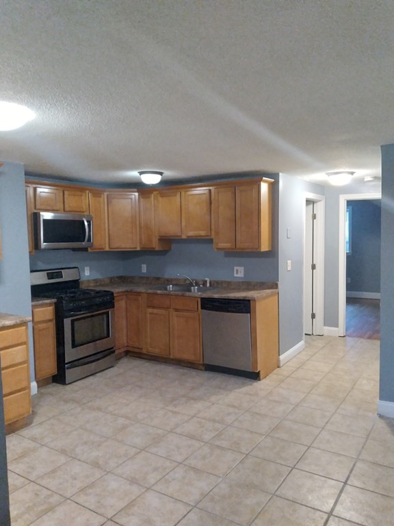a large kitchen with stainless steel appliances granite countertop a stove granite counter tops and white cabinets