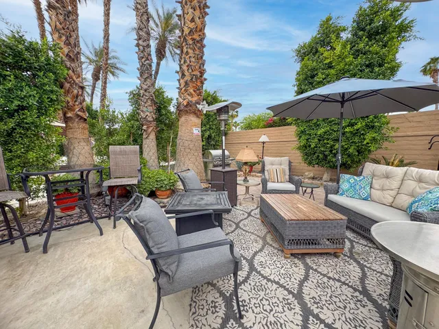 a view of a patio with couches and a table and chairs under an umbrella