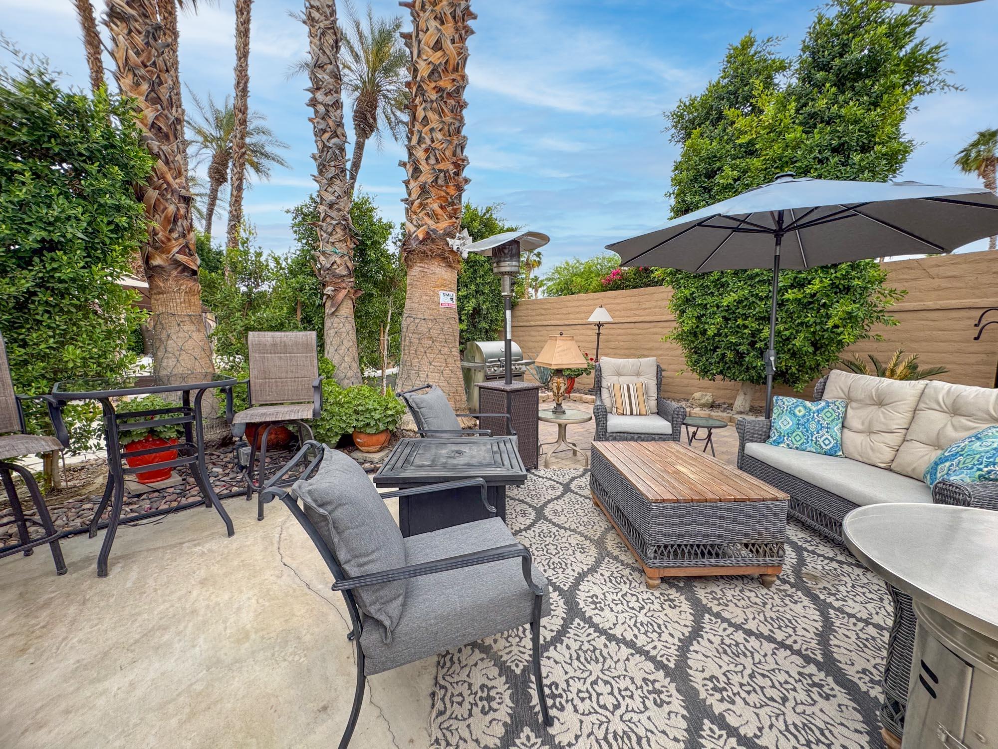 80394 Ave 48, Unit 90 Indio, CA 92201 - Photo 2 of 29 a view of a patio with couches and a table and chairs under an umbrella