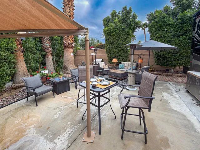 a view of patio with chairs and tables under an umbrella