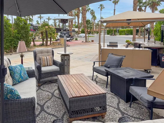 a view of a patio with couches table and chairs under an umbrella