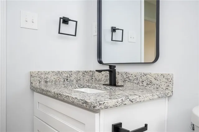 a bathroom with a granite countertop sink toilet and mirror