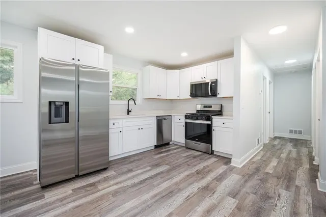 a kitchen with granite countertop a refrigerator and a stove top oven