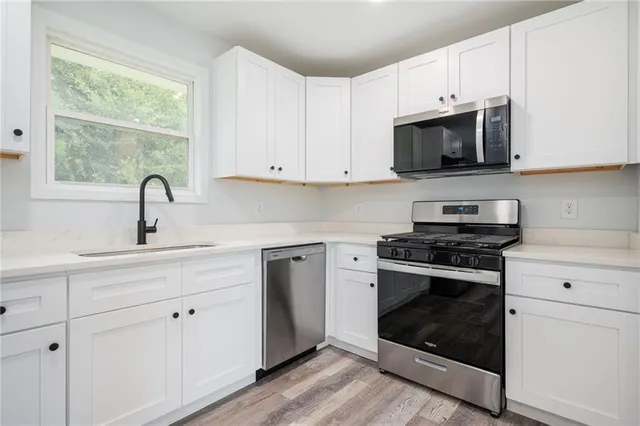 a kitchen with white cabinets and appliances