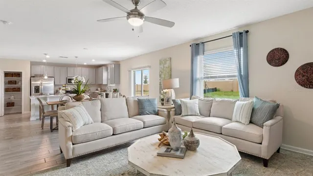 a living room with furniture kitchen view and a large window