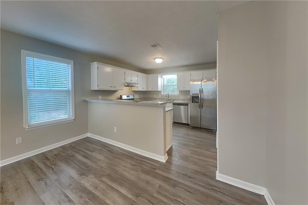 335 Olde Bridge Way Johns Creek, GA 30022 - Photo 6 of 19 a kitchen with stainless steel appliances granite countertop a stove top oven a sink dishwasher and a refrigerator with wooden floor