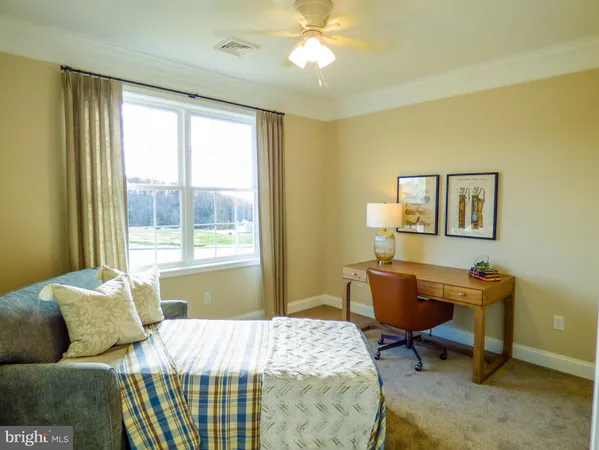 a bedroom with a bed a desk and chair with a window