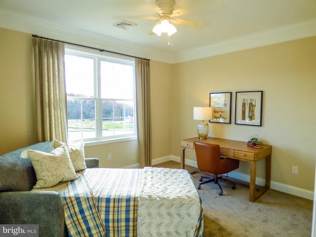 a bedroom with a bed a desk and chair with a window