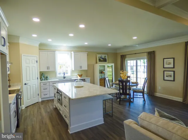 a living room with stainless steel appliances granite countertop furniture wooden floor and a view of kitchen