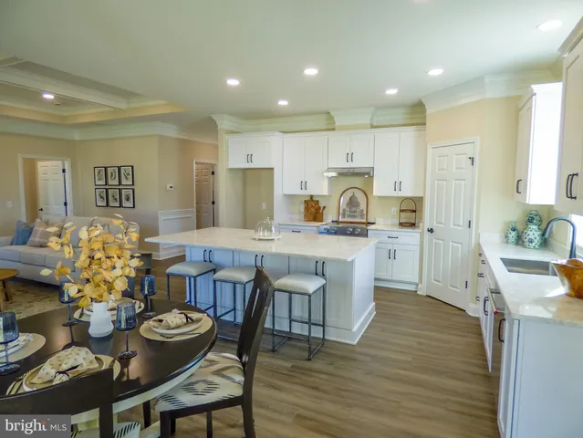 a large kitchen with kitchen island granite countertop a dining table chairs and white cabinets