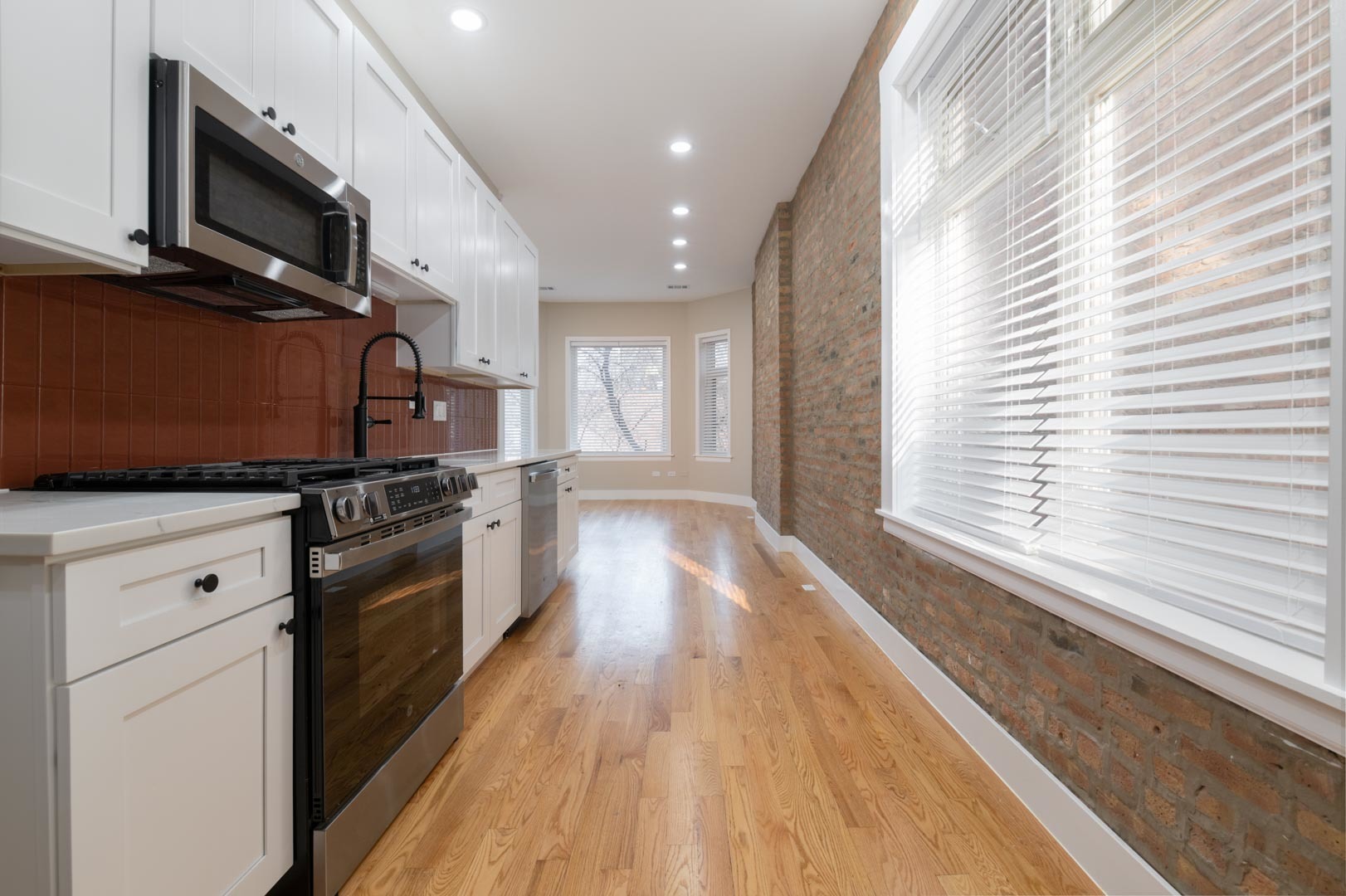 1303 West Flournoy Street, Unit 2F Chicago, IL 60607 - Photo 7 of 16 a kitchen with stainless steel appliances a stove a microwave and white cabinets