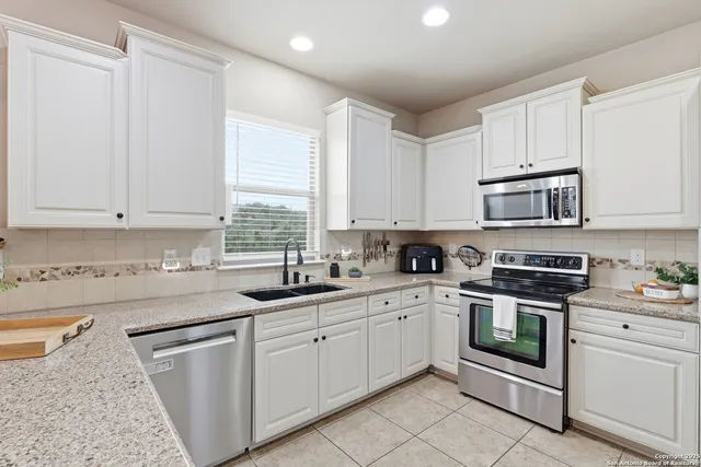 a kitchen with white cabinets appliances and a sink