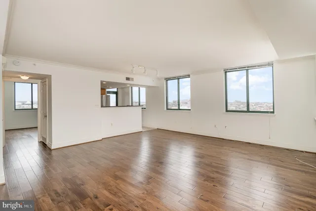 an empty room with wooden floor and windows