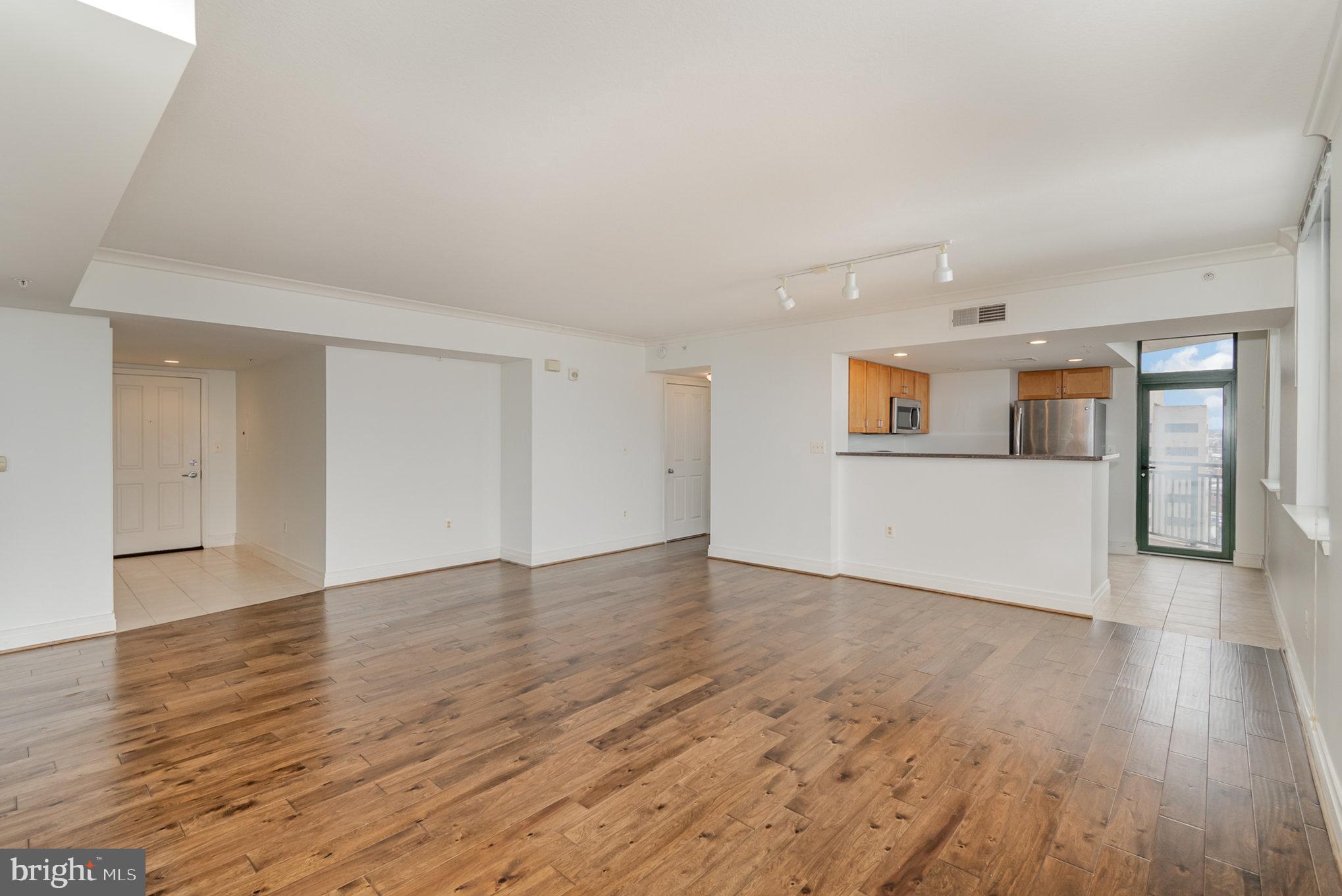 414 Water Street, Unit 1512 Baltimore, MD 21202 - Photo 6 of 28 a view of a big room with wooden floor and a kitchen
