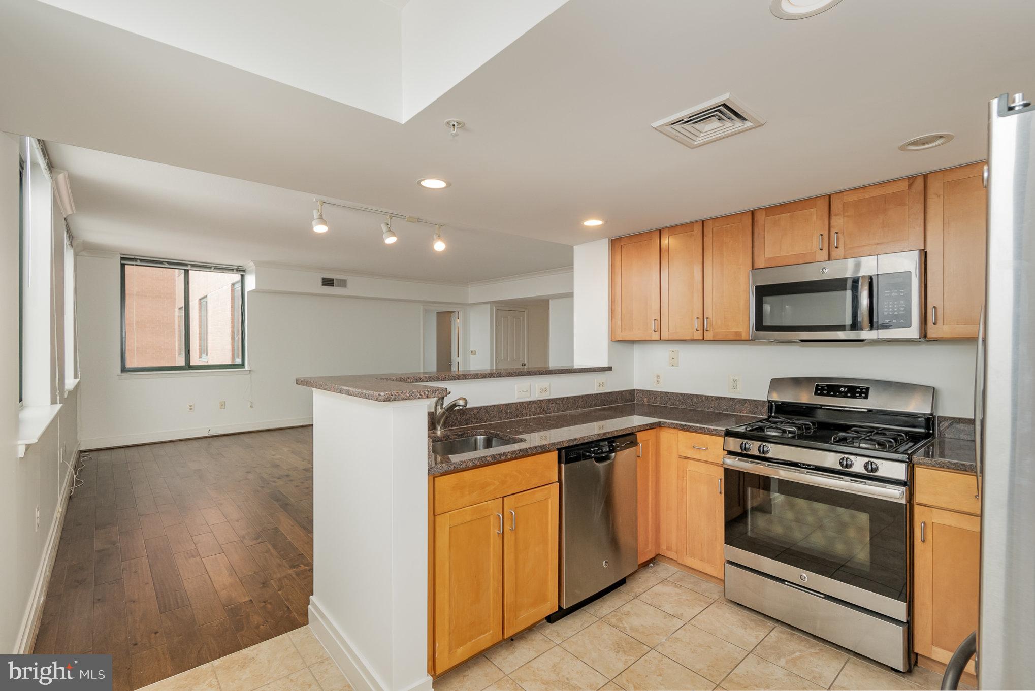 414 Water Street, Unit 1512 Baltimore, MD 21202 - Photo 10 of 28 a kitchen with granite countertop a stove top oven and cabinets