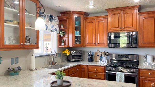 1797 Sunset Road Enoch, UT 84721 - Photo 11 of 80 Kitchen featuring light wood cabinetry with glass-front accents, stainless steel appliances including a range and microwave, light-toned countertops, and a stainless steel sink with a gooseneck faucet