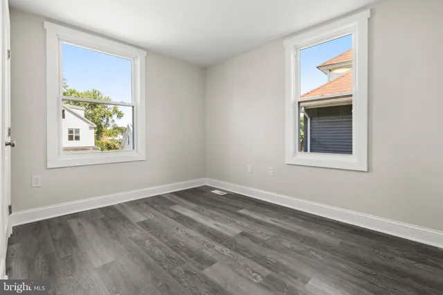 a view of an empty room with window and wooden floor