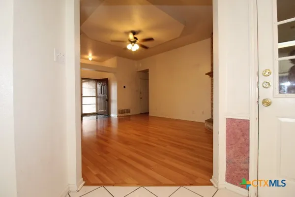 a view of an empty room with wooden floor and a window