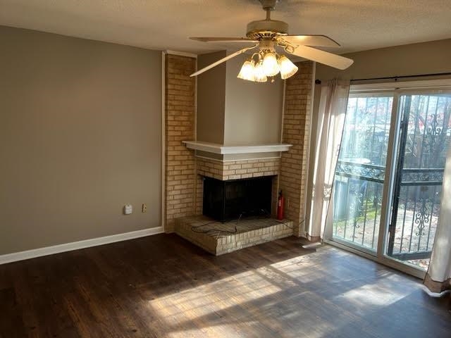 4795 Winchester Road Memphis, TN 38118 - Photo 4 of 7 Brick fireplace featuring a white mantel, wood-finish flooring, and a ceiling fan with integrated lighting