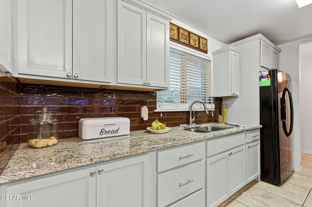 a kitchen with granite countertop a sink a stove and cabinets