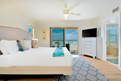 a bedroom with a large bed and a flat tv screen on dresser