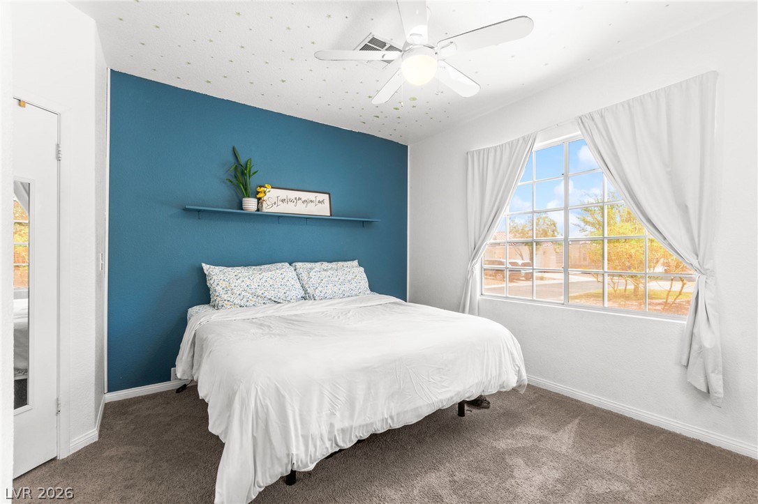7353 Ridge Star Court Las Vegas, NV 89131 - Photo 28 of 36 A comforting bedroom with a striking accent wall, offering a pleasant view of the neighborhood through a large window.