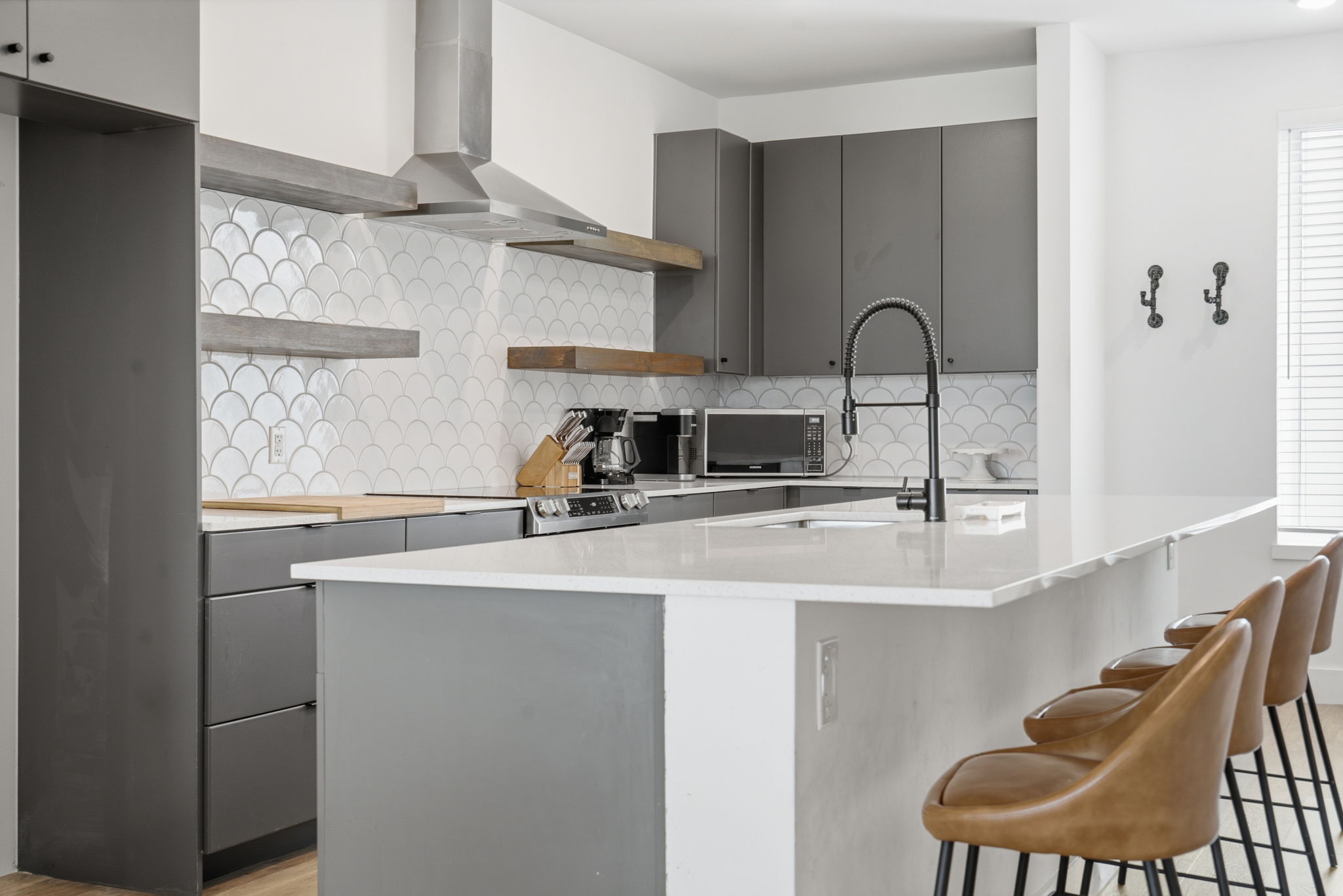 2709 East 5th Street, Unit 1306 Austin, TX 78702 - Photo 7 of 28 A contemporary kitchen features sleek gray cabinetry, integrated appliances, and a convenient kitchen island with seating.