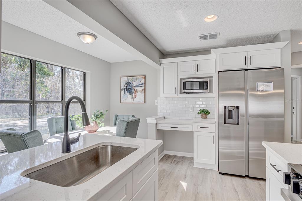 900 Highway 630 East Frostproof, FL 33843 - Photo 14 of 56 a kitchen with a refrigerator sink and white cabinets with wooden floor