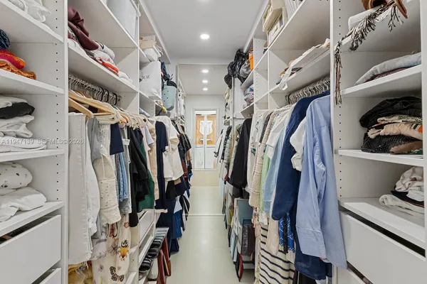 a view of walk in closet with clothes and shoes