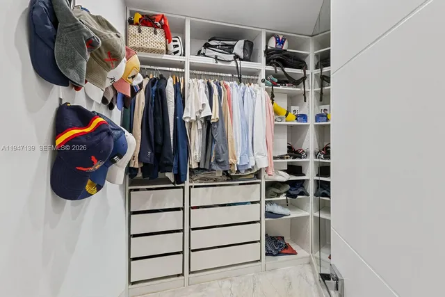 a view of walk in closet with clothes and shoes