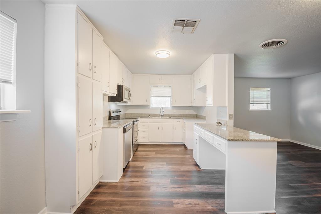 3328 Hedrick Street Fort Worth, TX 76111 - Photo 12 of 28 a large white kitchen with granite countertop a sink and dishwasher a refrigerator with wooden floors