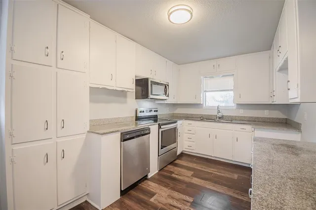 a kitchen with granite countertop white cabinets and white appliances