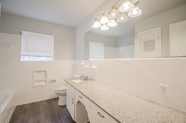 a bathroom with a granite countertop sink a toilet and a mirror