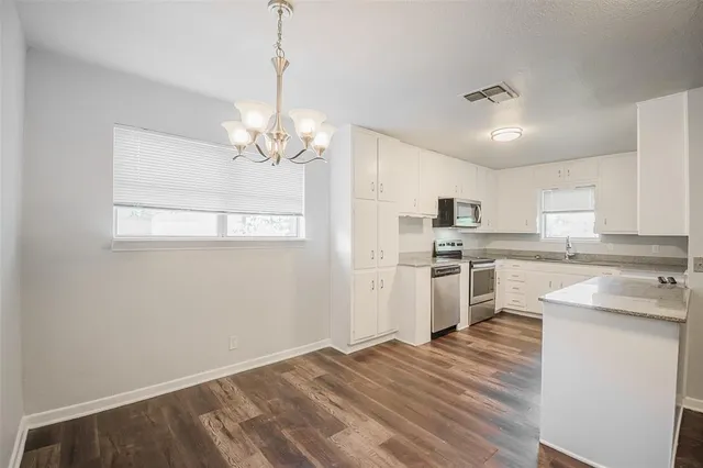 a kitchen with granite countertop a sink cabinets stainless steel appliances and a window