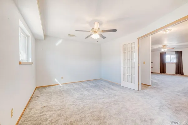 an empty room with chandelier fan and windows