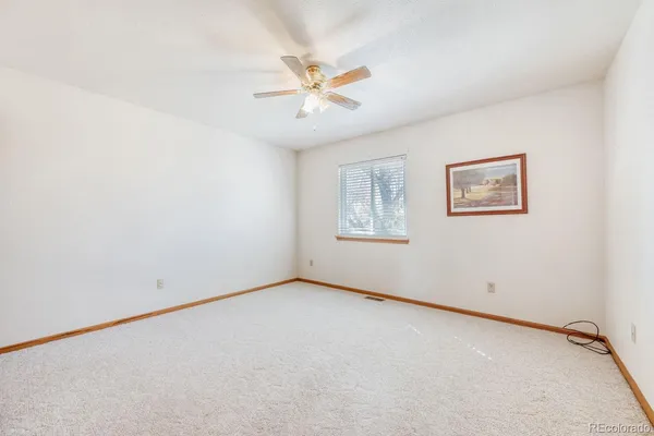 an empty room with a window and a fan