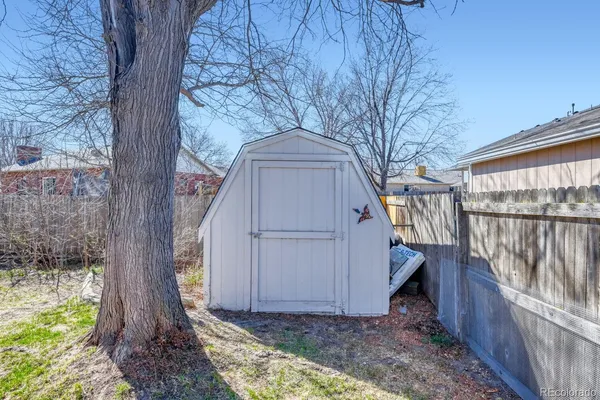a backyard of a house with large trees and wooden fence