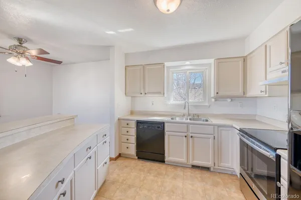 a kitchen with a sink dishwasher a stove and white cabinets