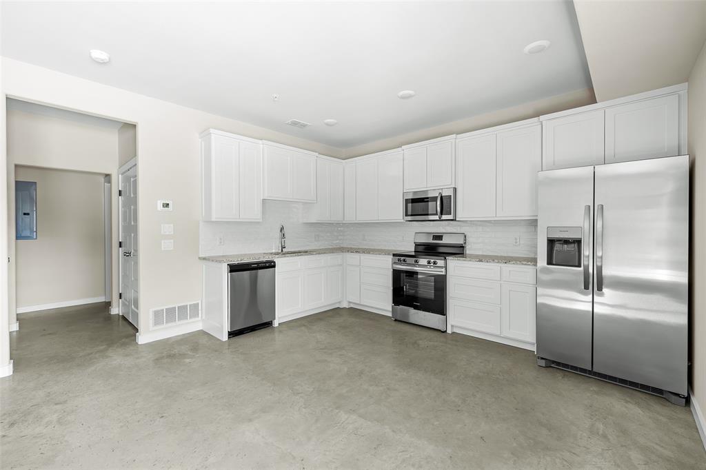 2290 West Tarleton Street, Unit 105 Stephenville, TX 76401 - Photo 5 of 15 a kitchen with white cabinets and stainless steel appliances