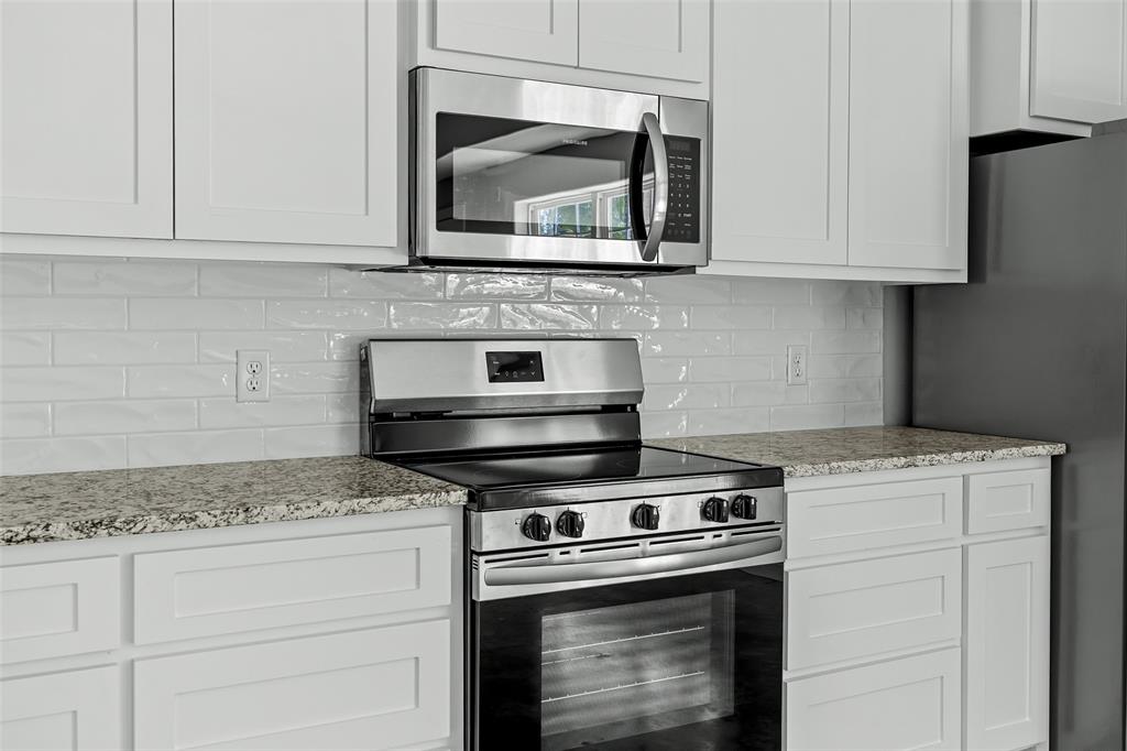 2290 West Tarleton Street, Unit 105 Stephenville, TX 76401 - Photo 6 of 15 a kitchen with granite countertop white cabinets stainless steel appliances and a counter space