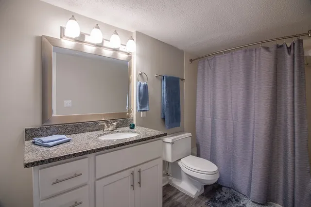a bathroom with a granite countertop sink toilet and mirror