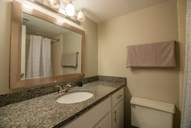 a bathroom with a granite countertop sink and a mirror