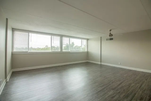 an empty room with wooden floor and windows
