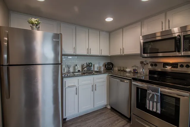 a kitchen with stainless steel appliances granite countertop a refrigerator a stove top oven a sink and dishwasher
