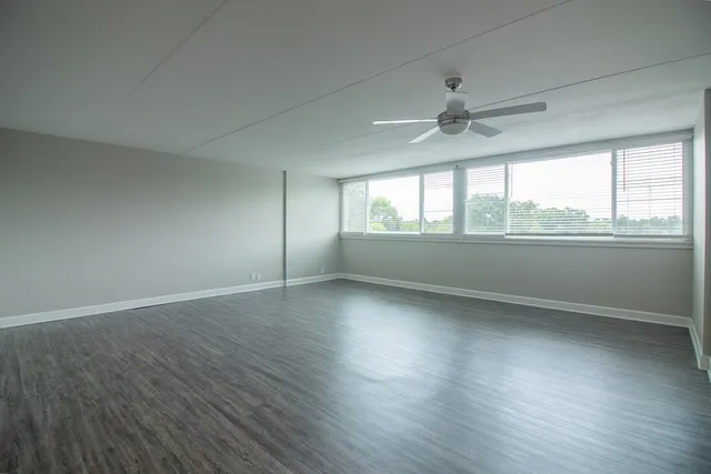 an empty room with wooden floor and windows