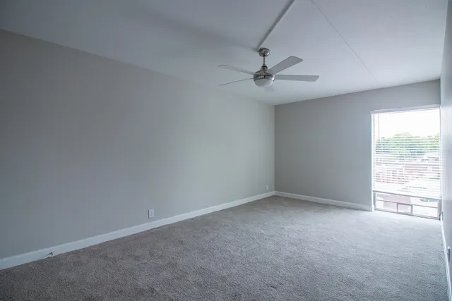 an empty room with a window and a fan