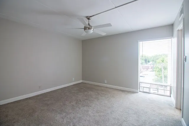 an empty room with a window and a fan