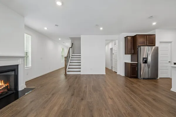 a view of a kitchen with a refrigerator a fireplace and wooden floor