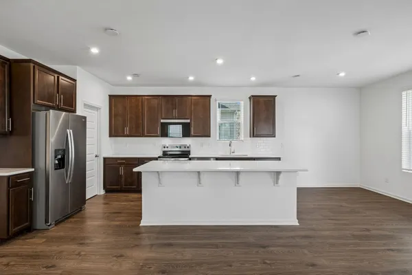 a large kitchen with stainless steel appliances a large counter top and a stove top oven