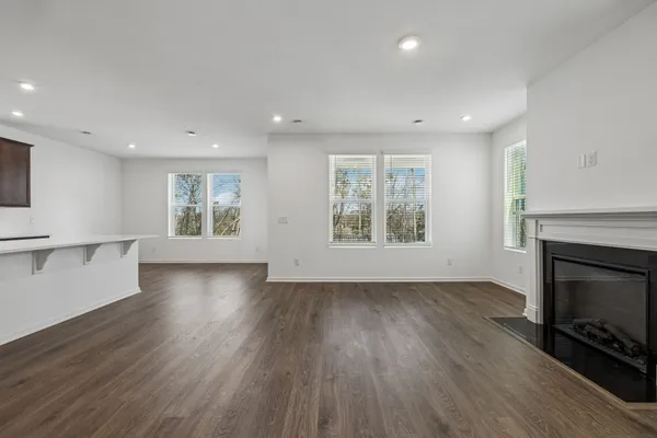 an empty room with wooden floor fireplace and windows